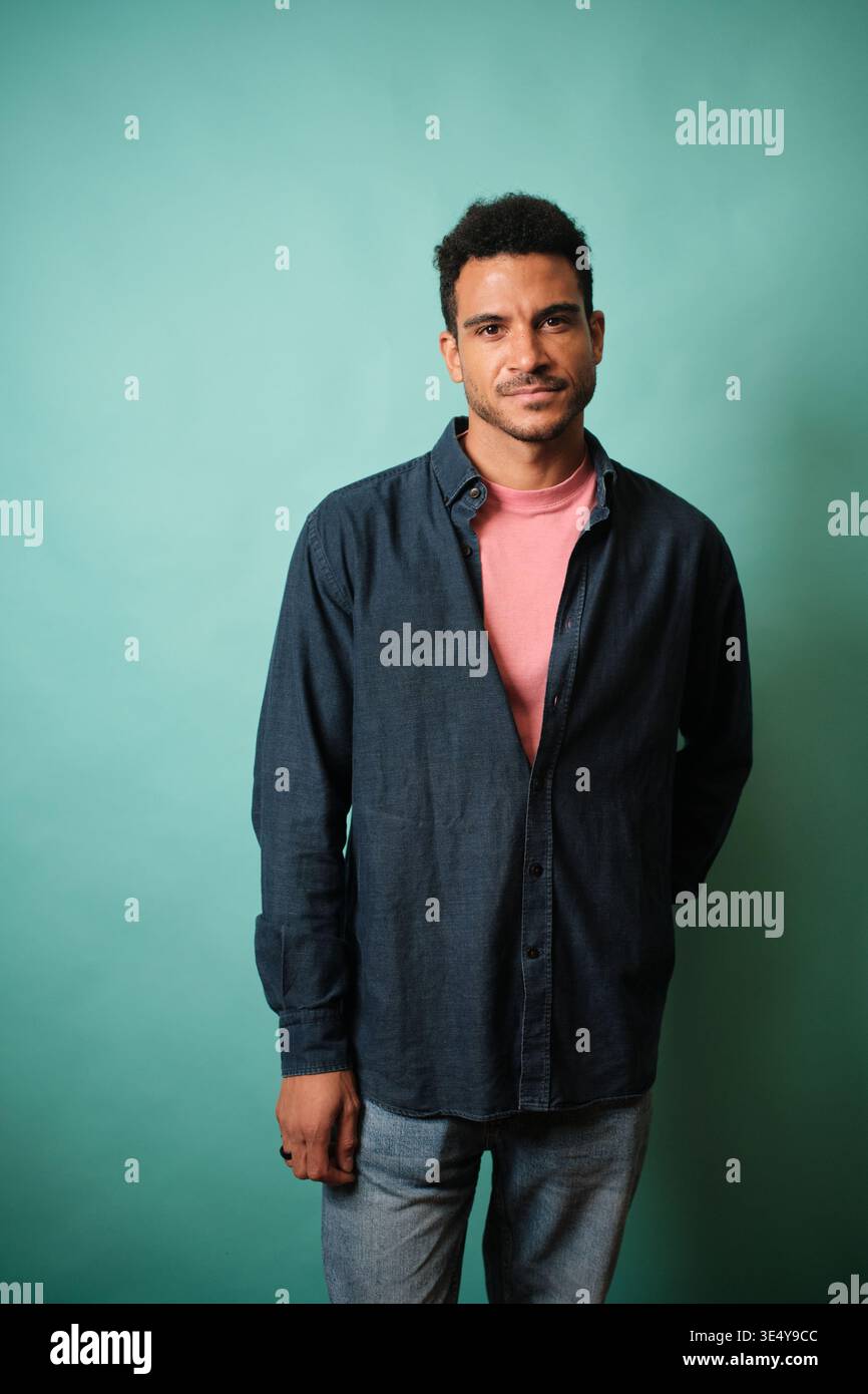 Confident young man standing against teal background Stock Photo