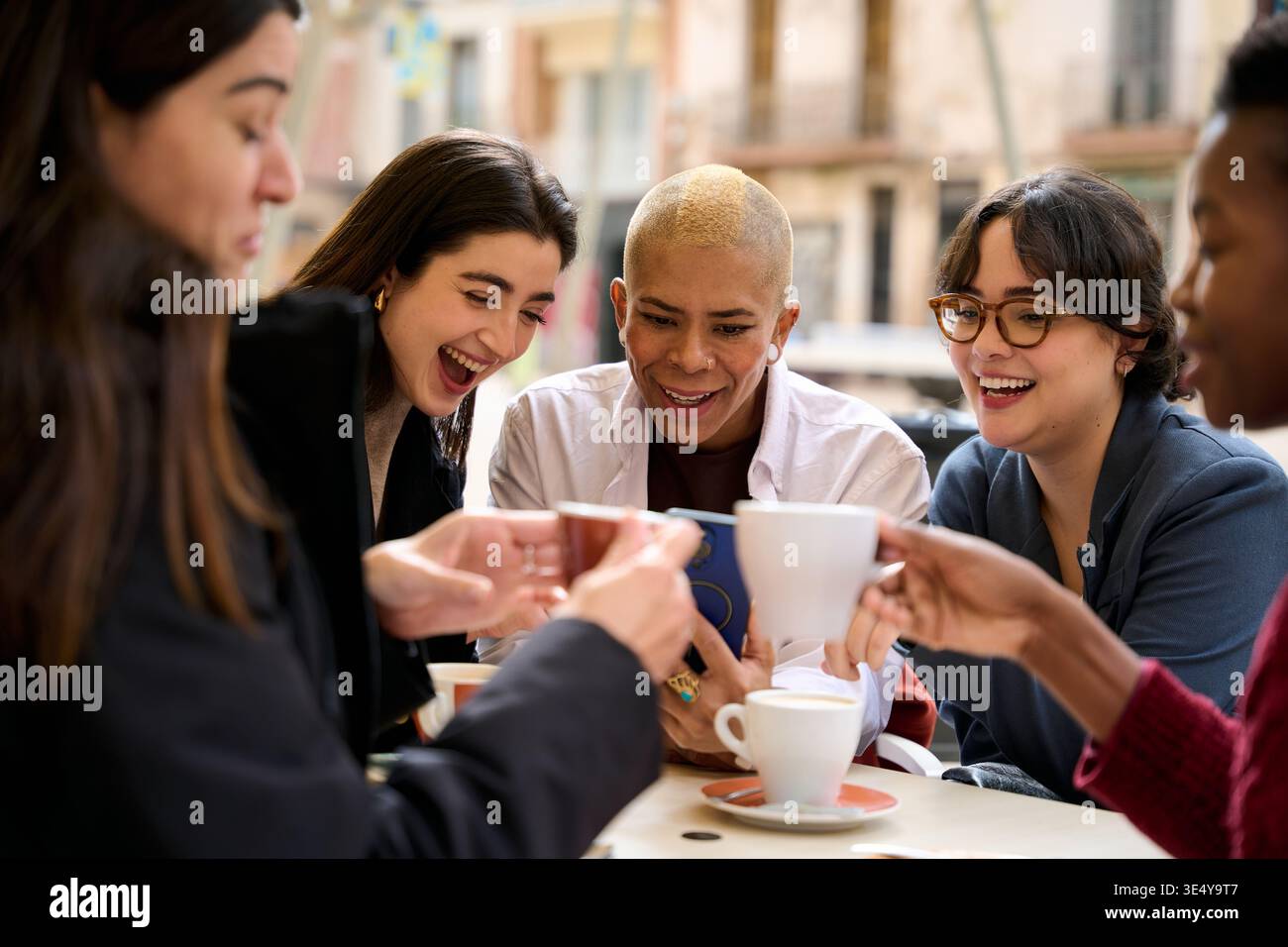 Diverse friends enjoying coffee sharing laughter at cafe Stock Photo