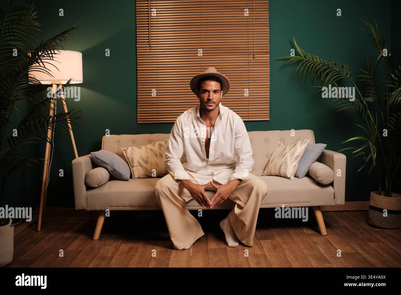 Stylish man sitting on sofa in cozy home Stock Photo