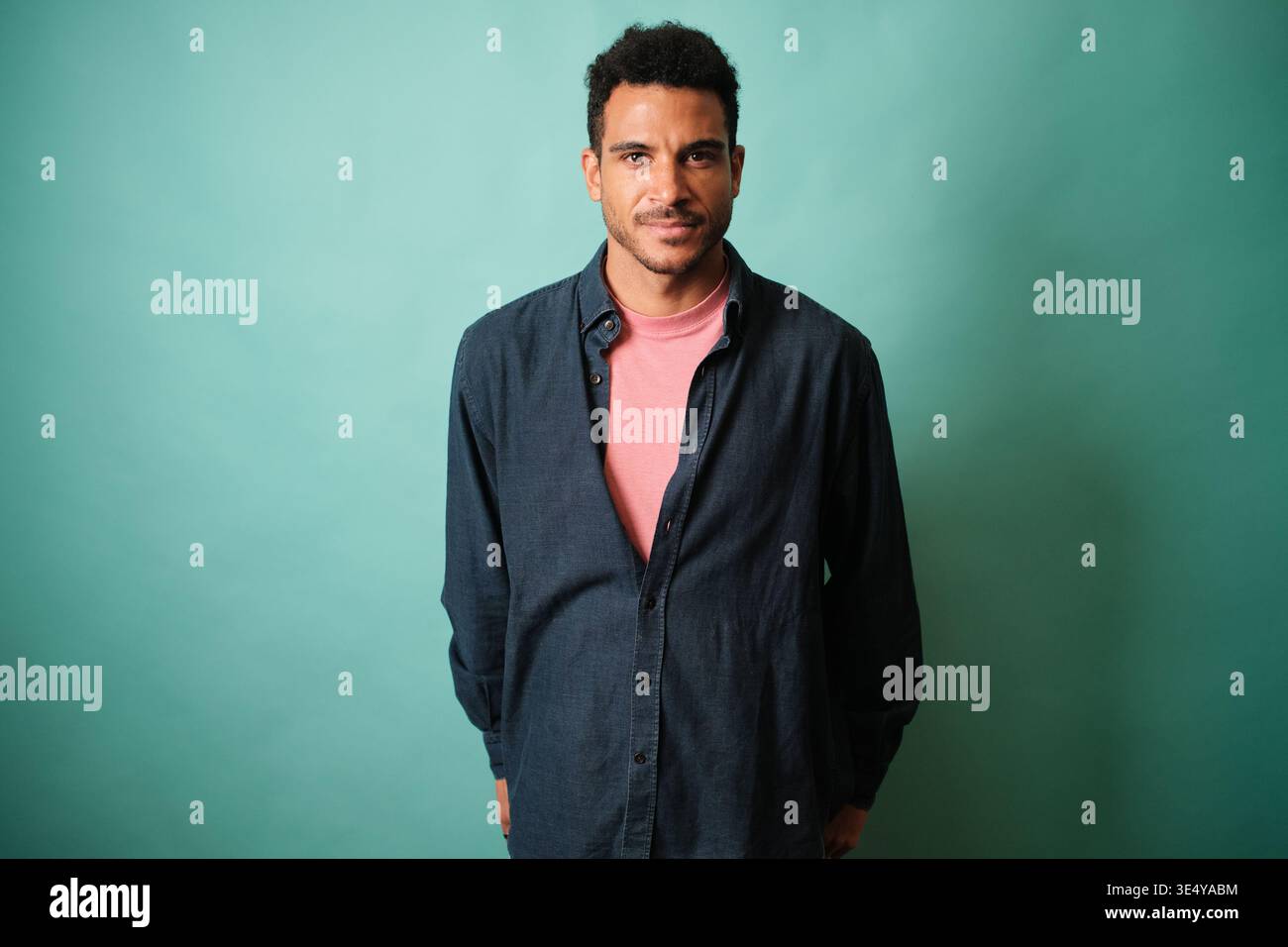 Confident young man posing against teal background Stock Photo