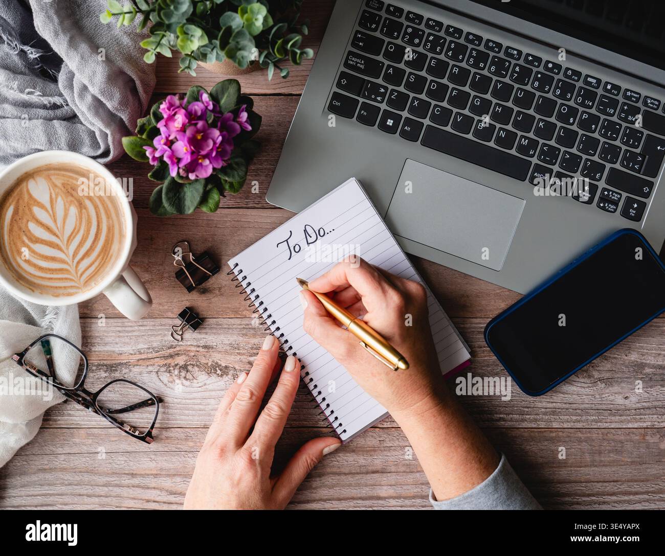 Top view hands writing on notepad near computer, phone on desk. Stock Photo