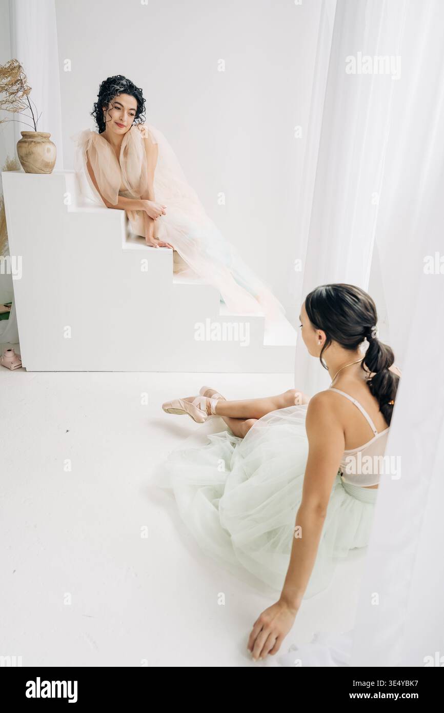 Two ballerinas sitting in minimalist studio space Stock Photo