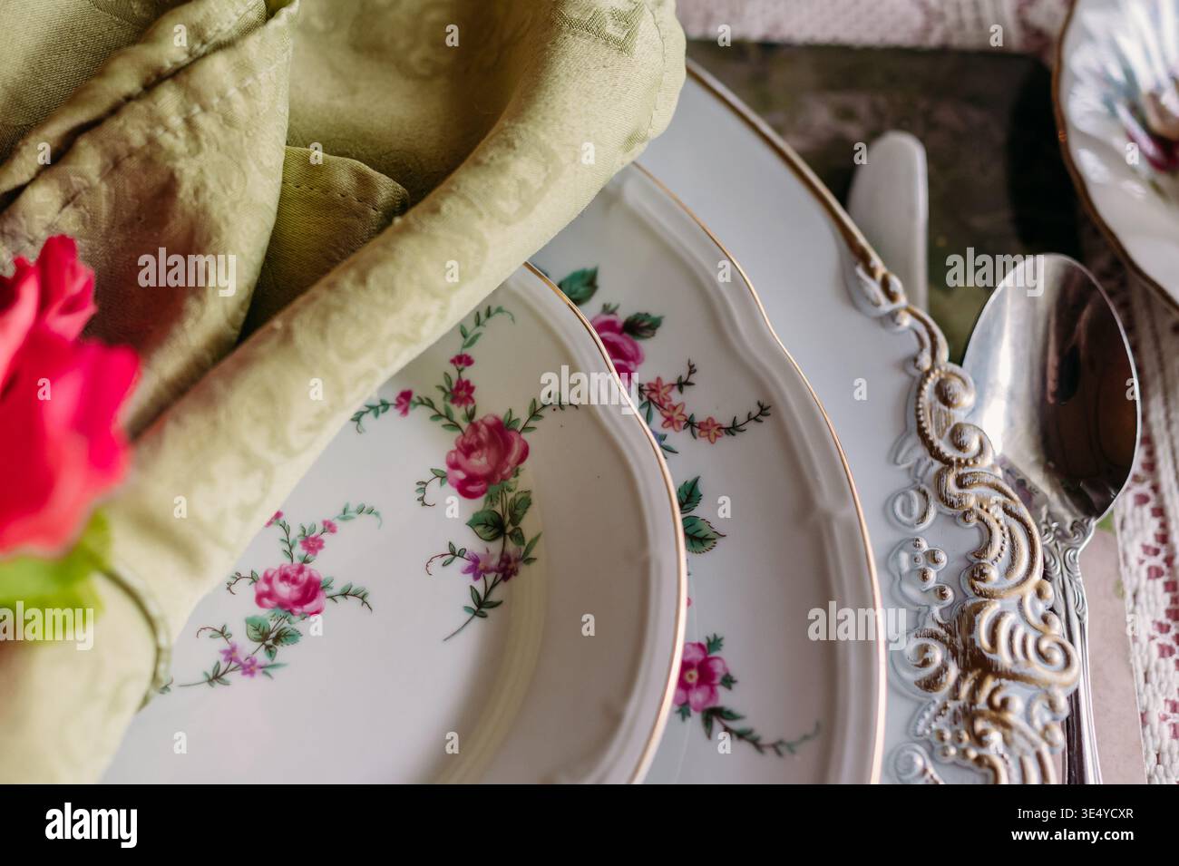 Close-up of vintage floral china with ornate silverware and napkin Stock Photo