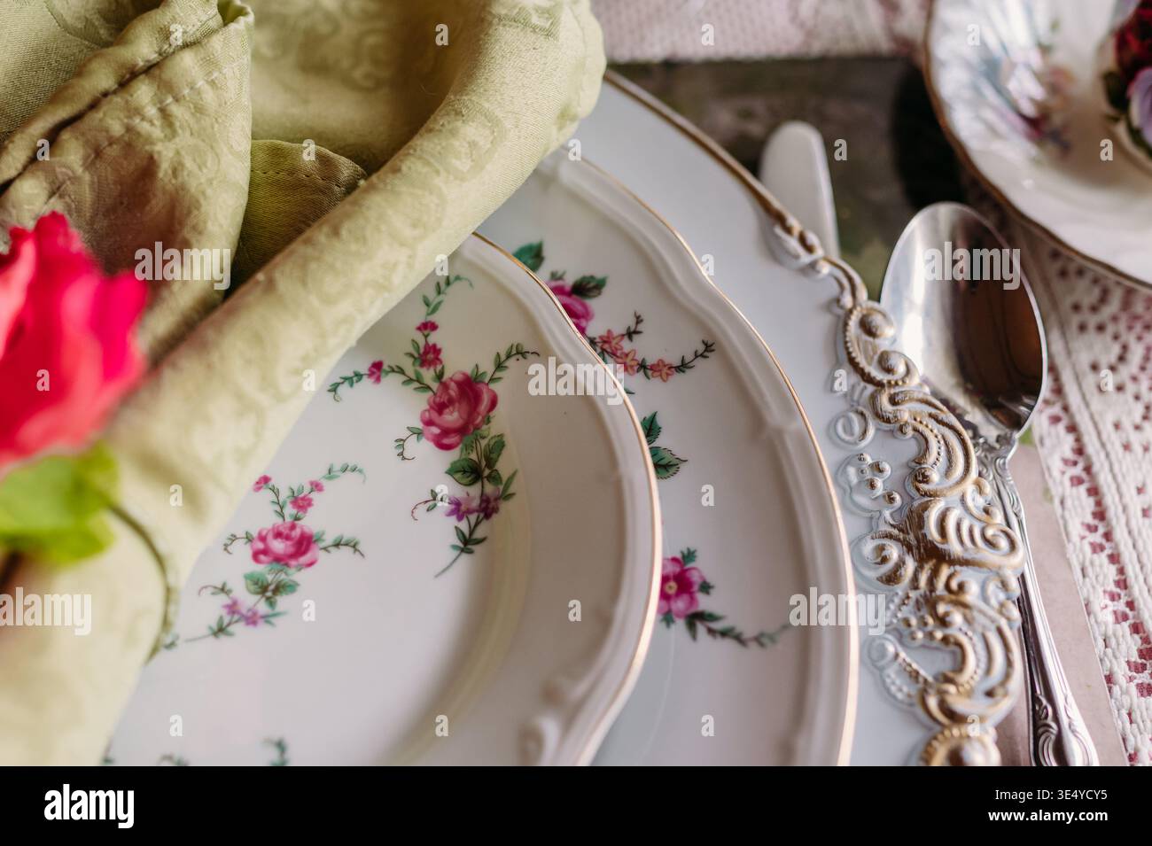 Close-up of vintage floral china with ornate silverware and napkin Stock Photo