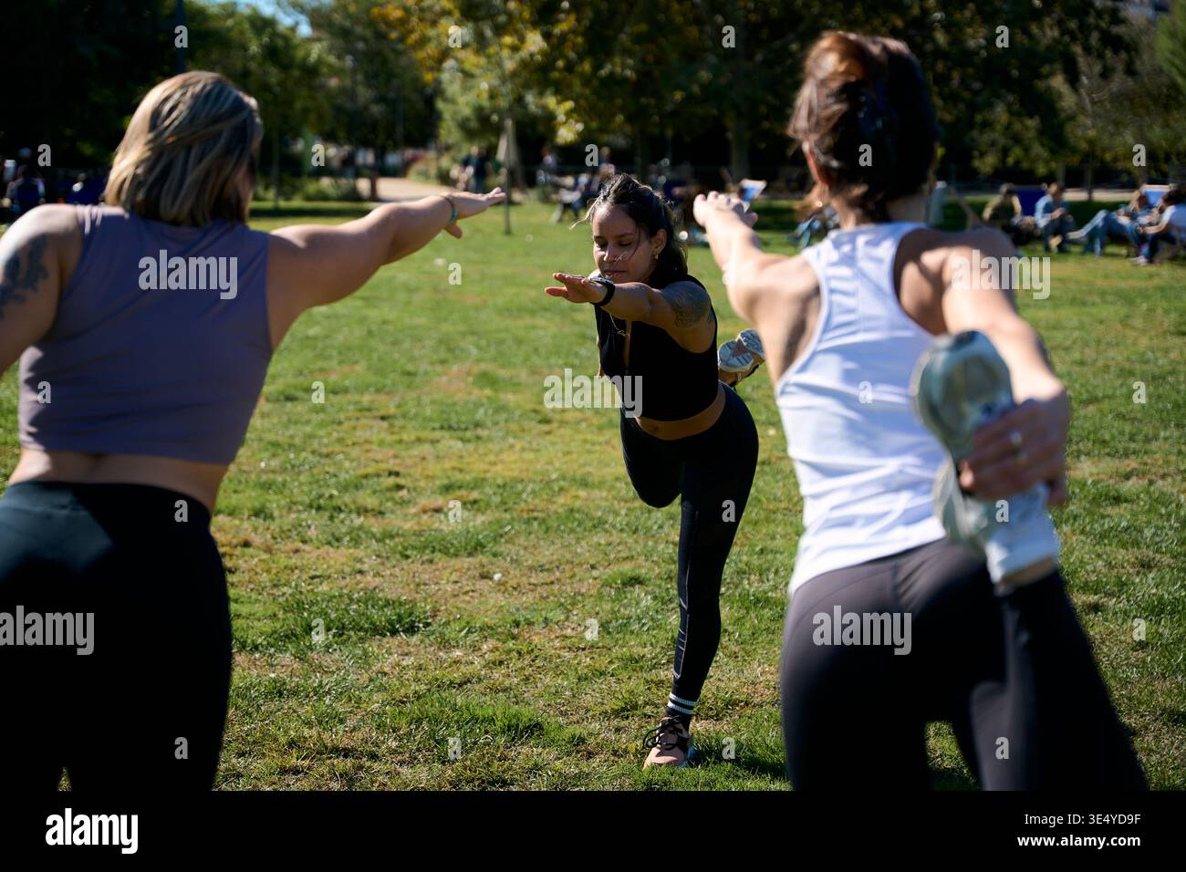 Three women practicing yoga in park balancing dancer pose Stock Photo