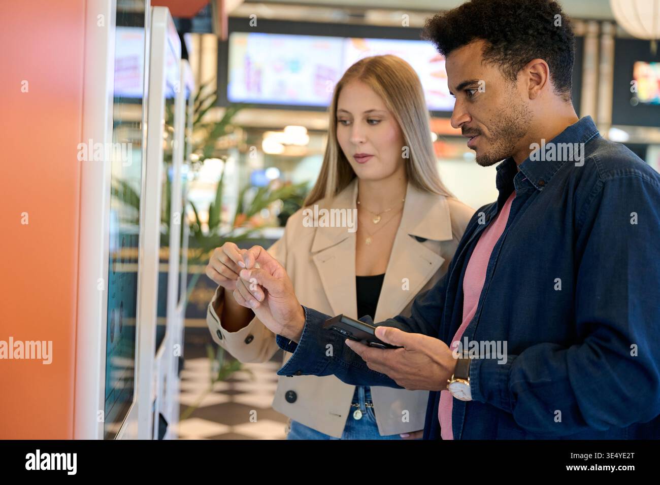 Couple using touch screen kiosk for ordering food Stock Photo