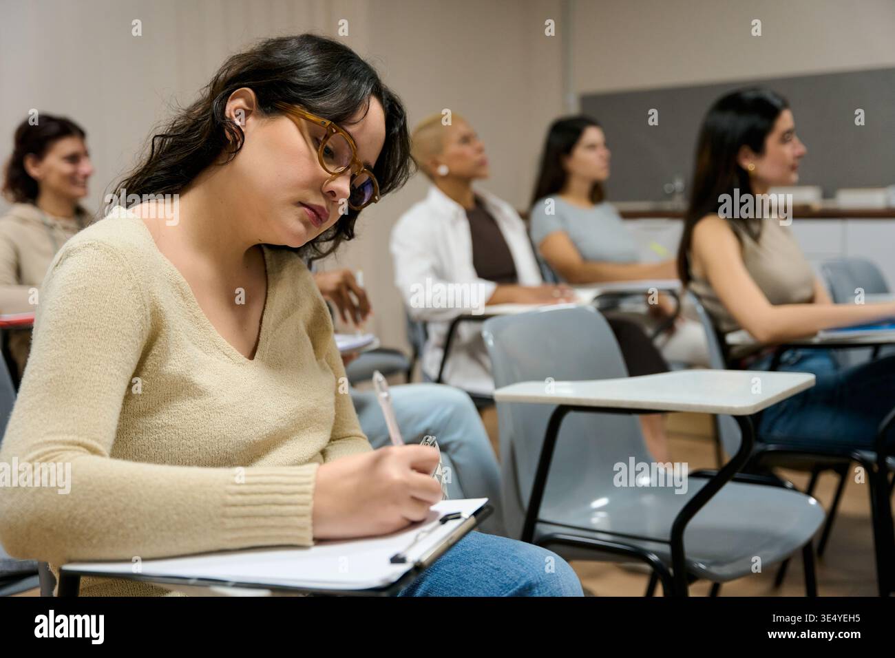 Female student writing notes during university lecture Stock Photo