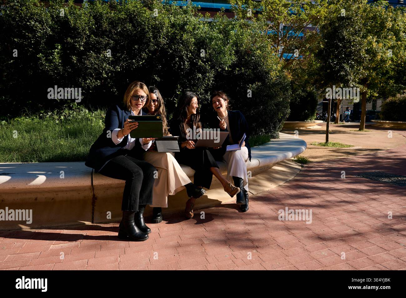 Female colleagues collaborating outdoors using digital technology Stock Photo