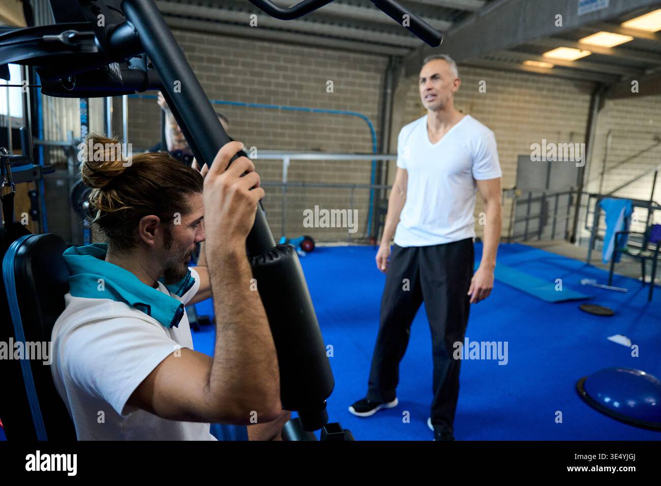 Personal trainer guiding man doing strength workout Stock Photo