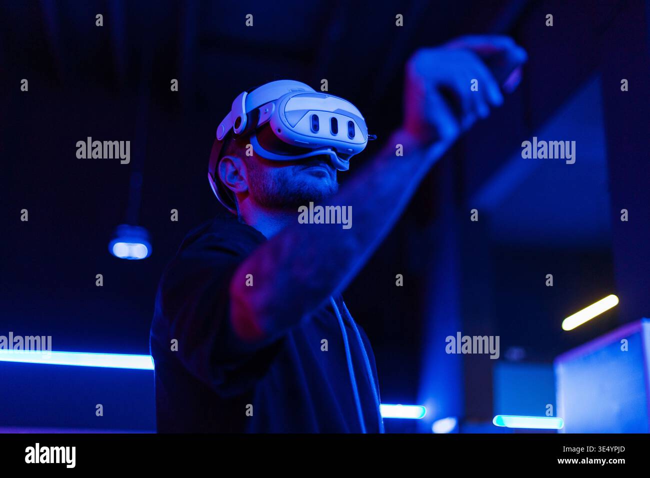 young man engages with a virtual world using a mixed reality spacial computer headset, symbolizing cutting-edge technology in gaming and immersive dig Stock Photo