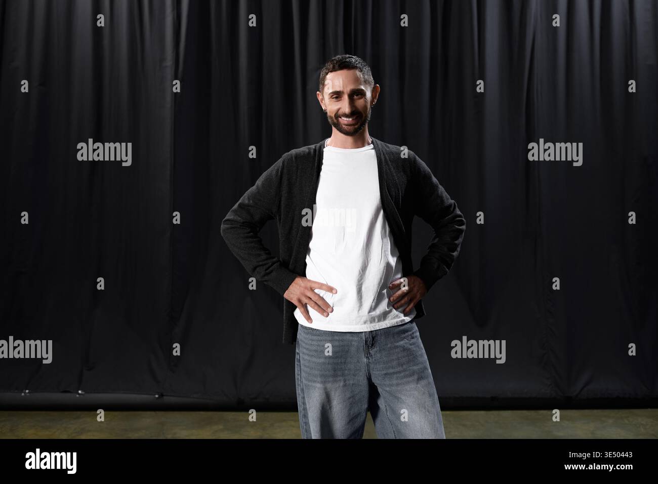 A handsome man stands confidently in a theater, ready to showcase his talent on stage. Stock Photo