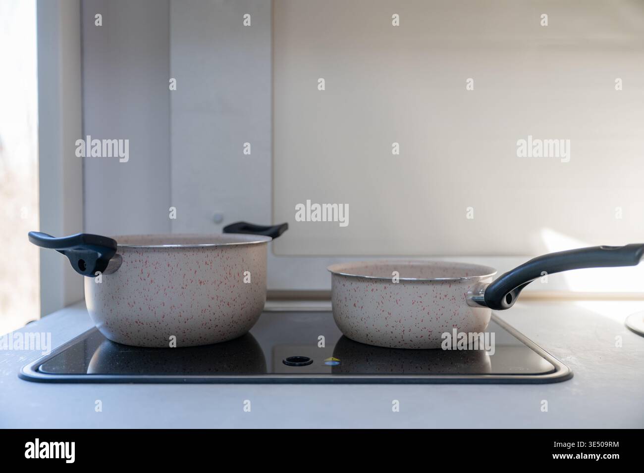 Modern kitchen cookware set with saucepan and pot on electric stove ...