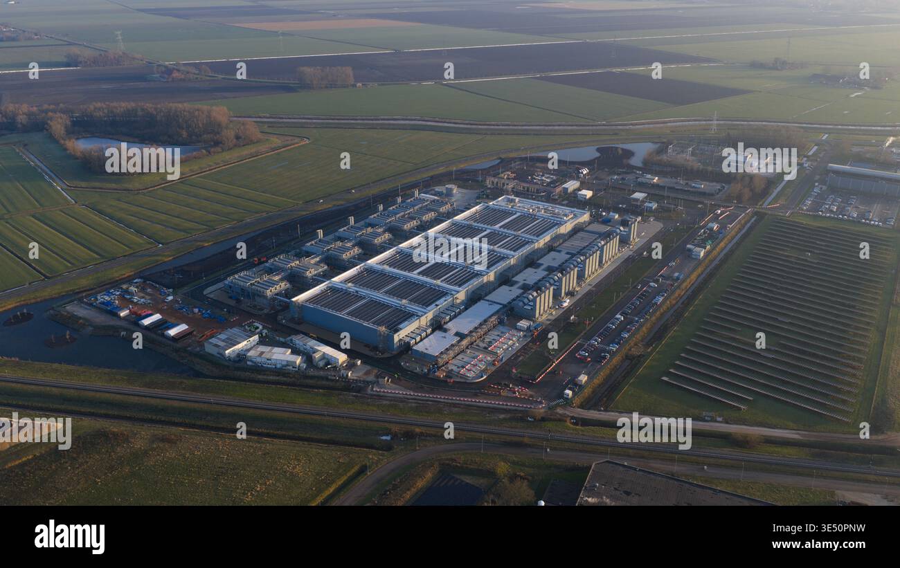 Aerial view of Datacenter Winschoten featuring massive industrial halls, cooling units, and solar panels surrounded by green agricultural fields in Wi Stock Photo