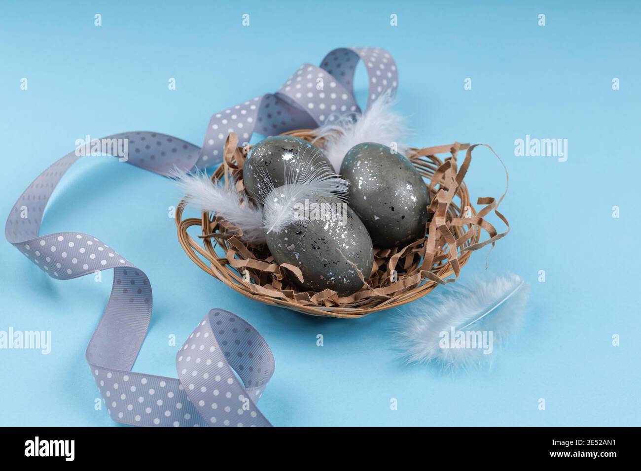 Easter holiday composition eggs nest feathers and ribbon Stock Photo