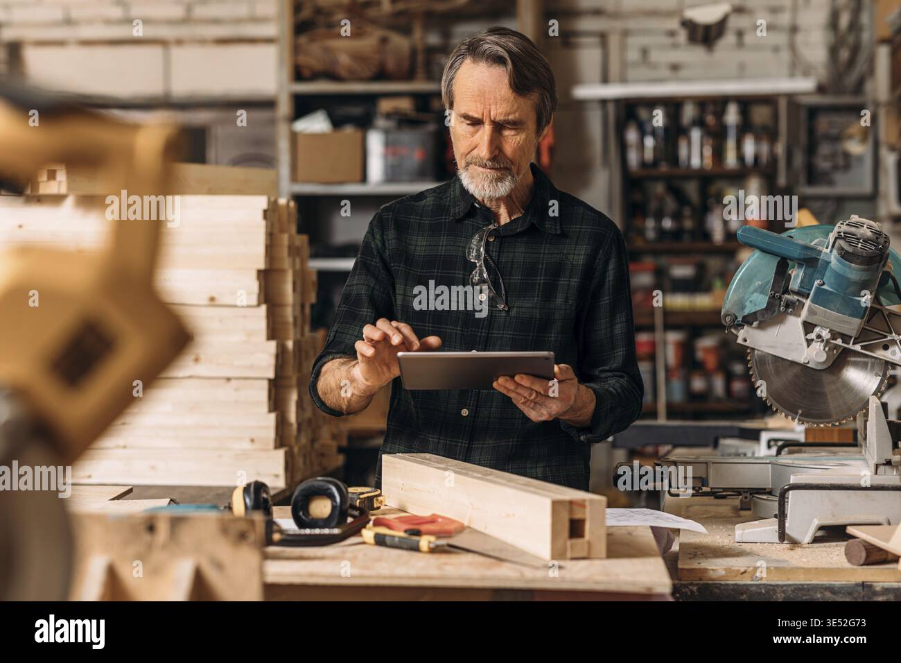 Senior carpenter using a digital tablet in his workshop Stock Photo