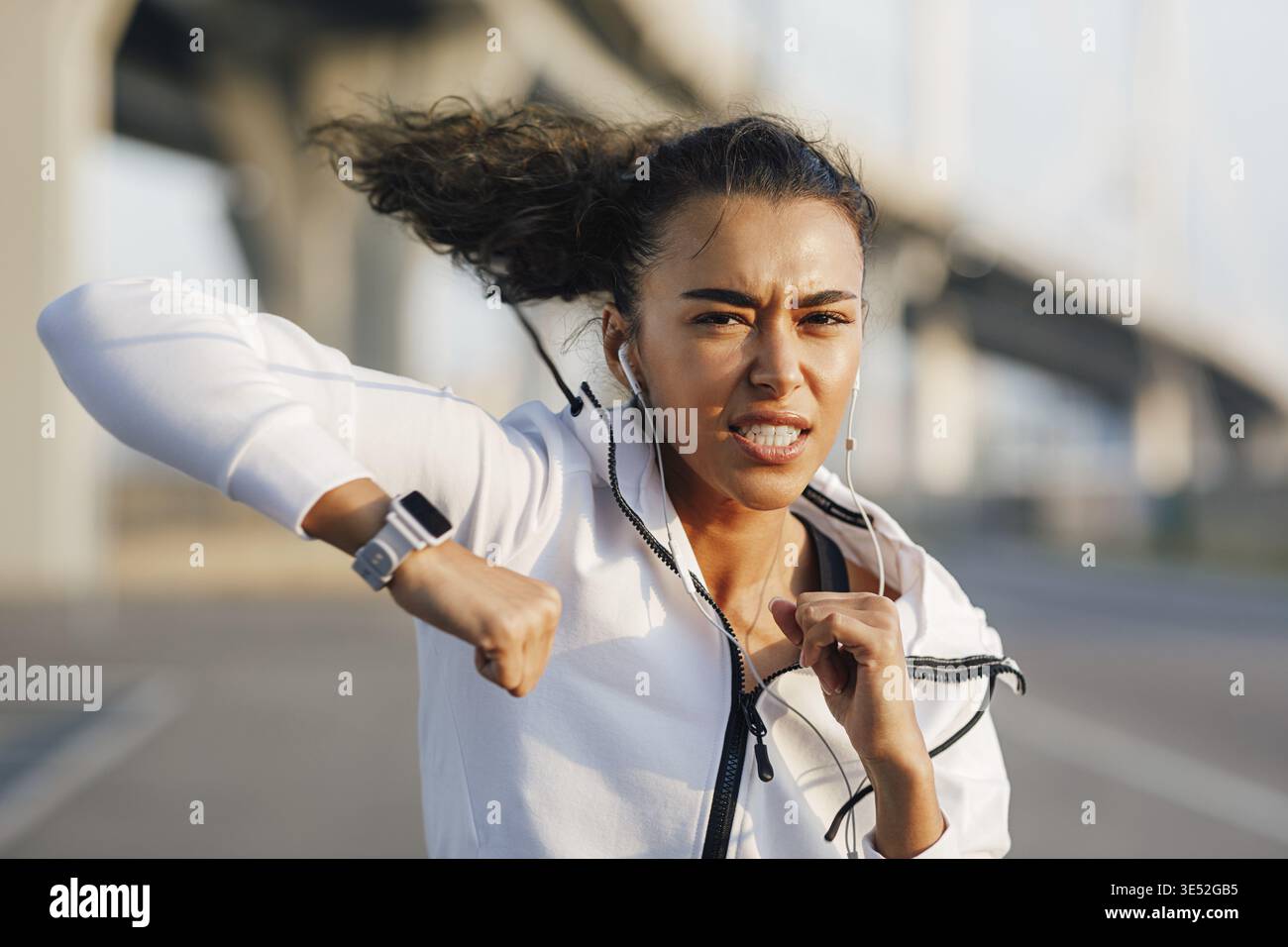 Strong young woman practicing boxing outdoors. Female boxer doing punches Stock Photo