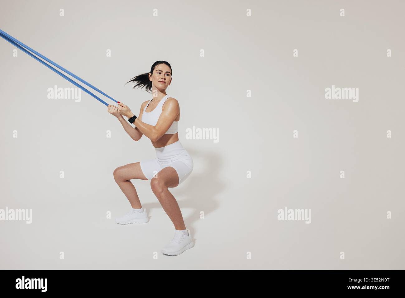 Young slim woman doing sit-ups and using a resistance band Stock Photo