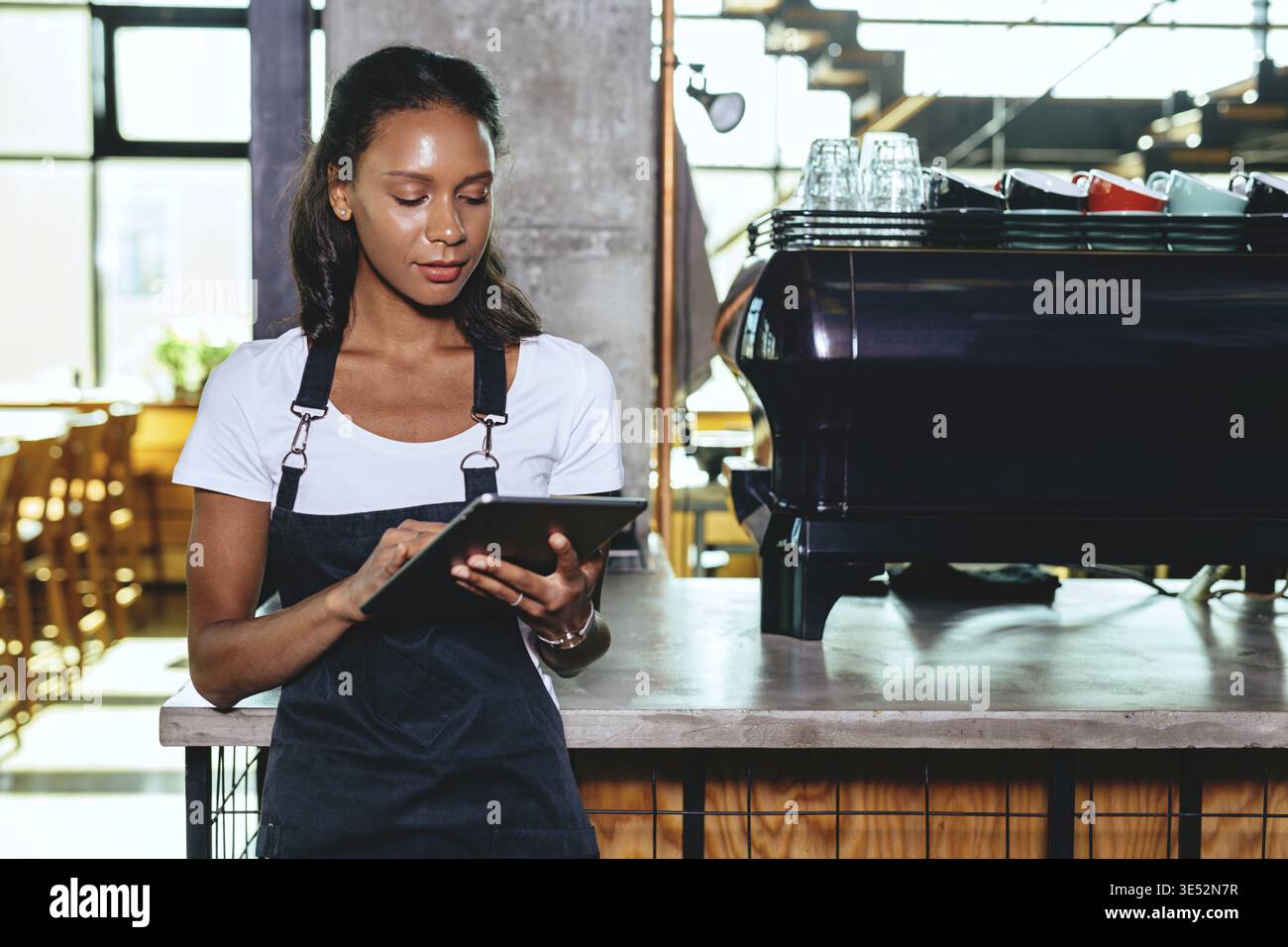 Young barista using digital tablet. Waitress standing by the coffee machine Stock Photo