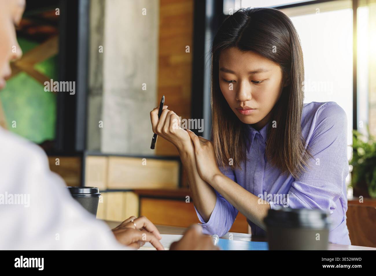 Two colleagues discussing in cafe, sitting at table Stock Photo