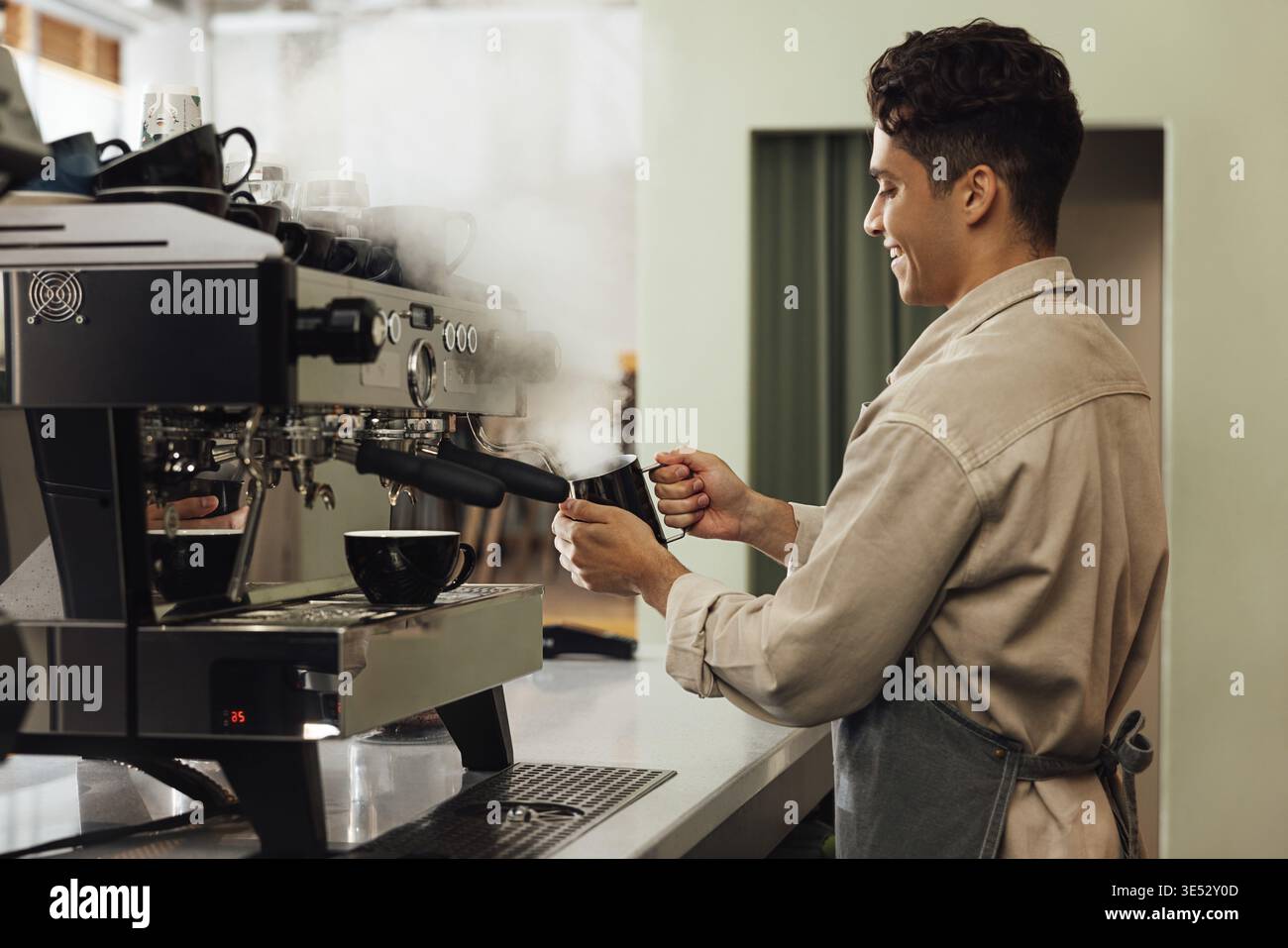 Side view of a barista using a coffee machine. Coffee shop owner preparing coffee Stock Photo