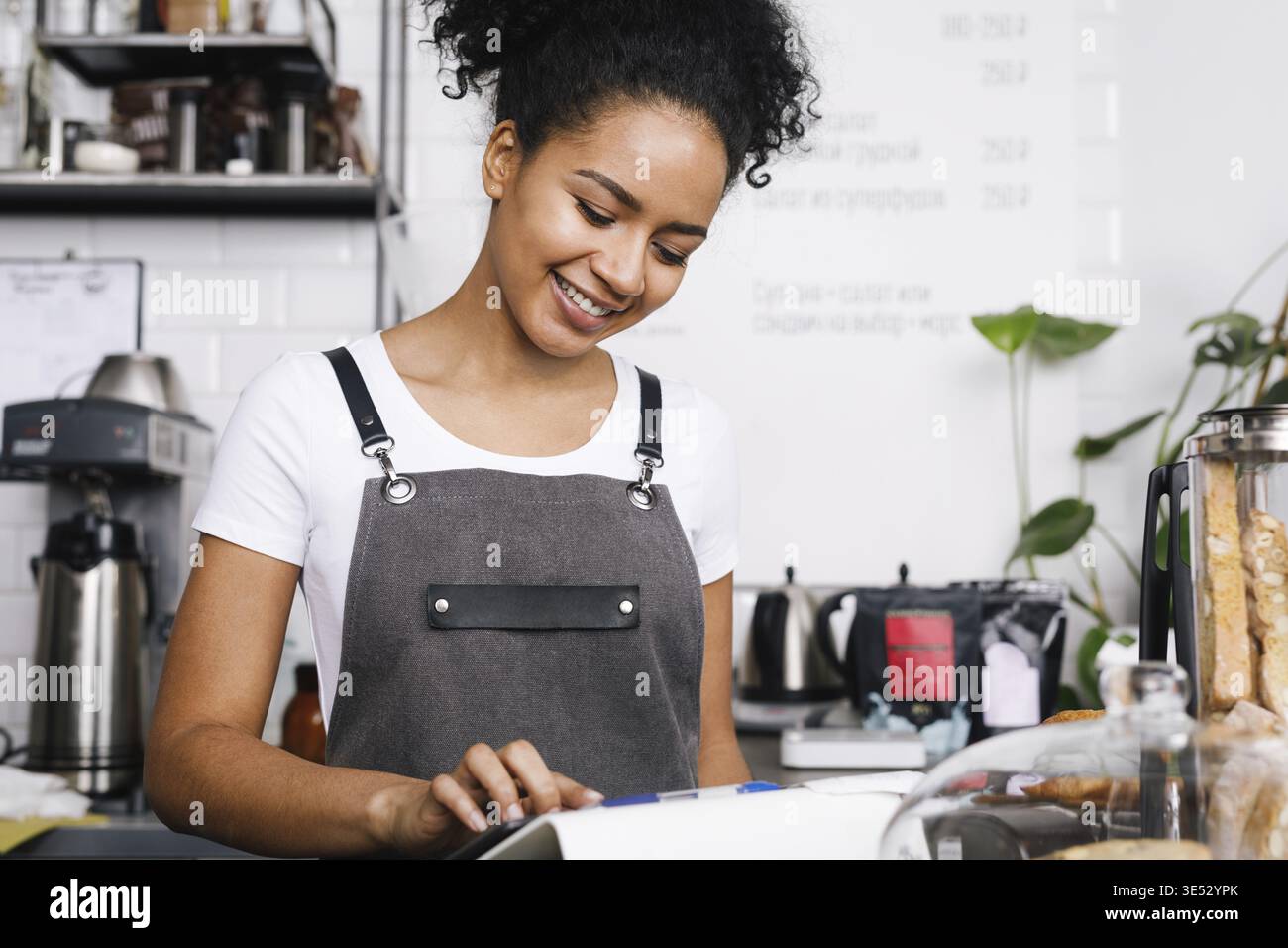 Smiling beautiful waitress using digital tablet in cafe Stock Photo