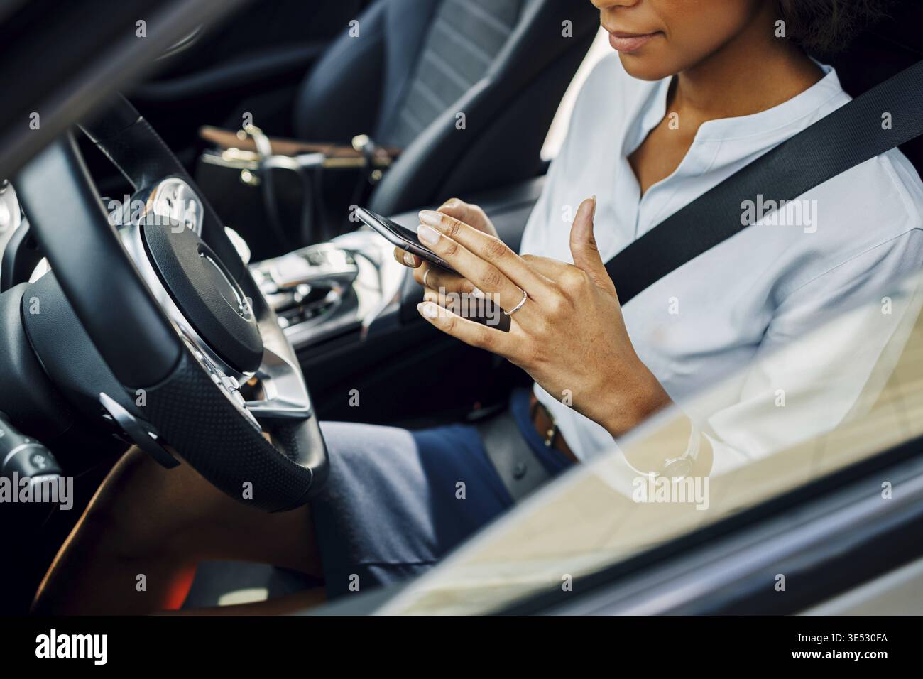 Unrecognizable woman using smartphone while sitting in car Stock Photo