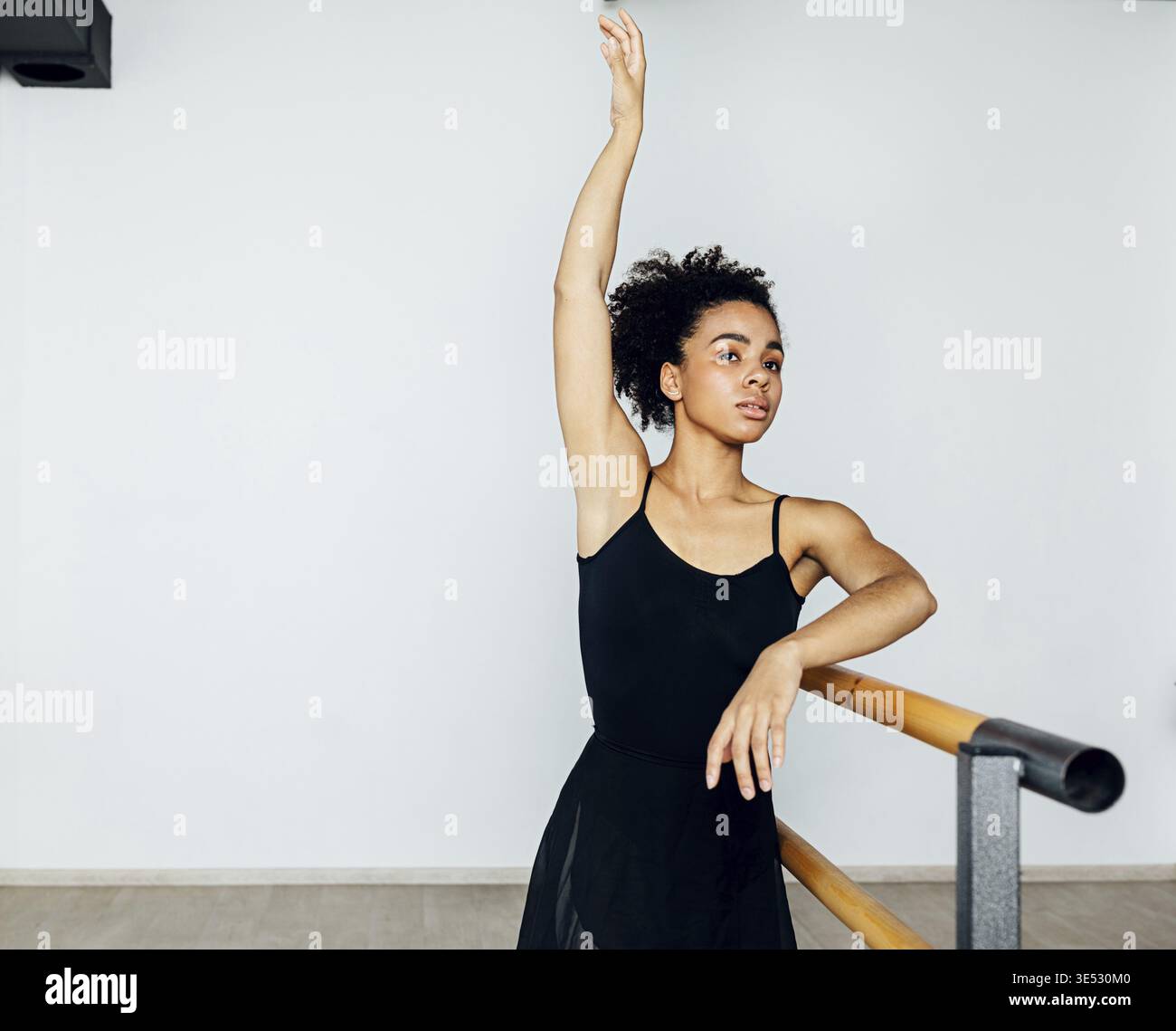 Professional ballet dancer practicing at barre in small studio Stock Photo