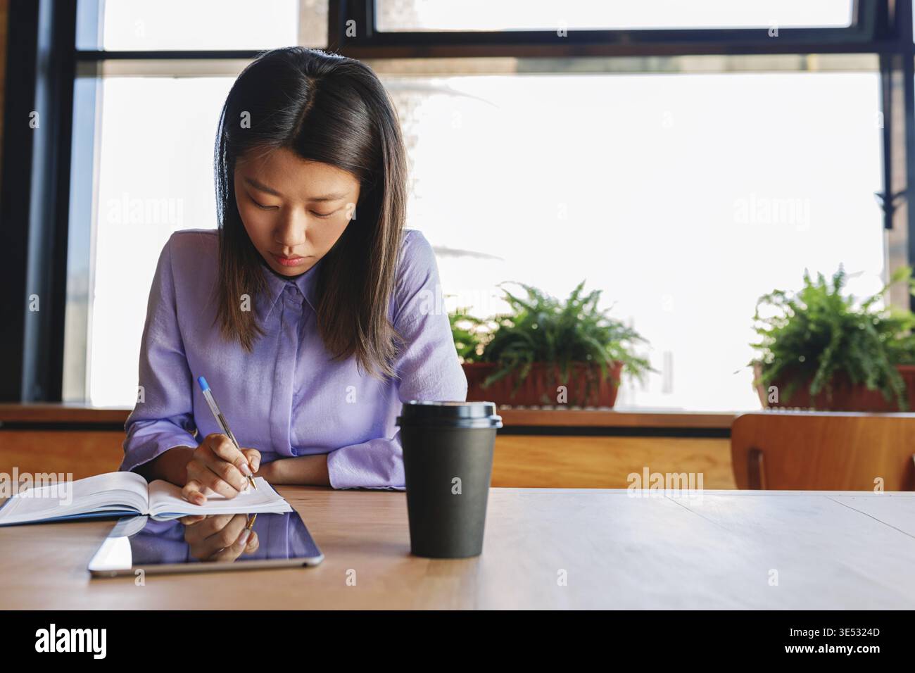 Young business woman making notes in cafe Stock Photo