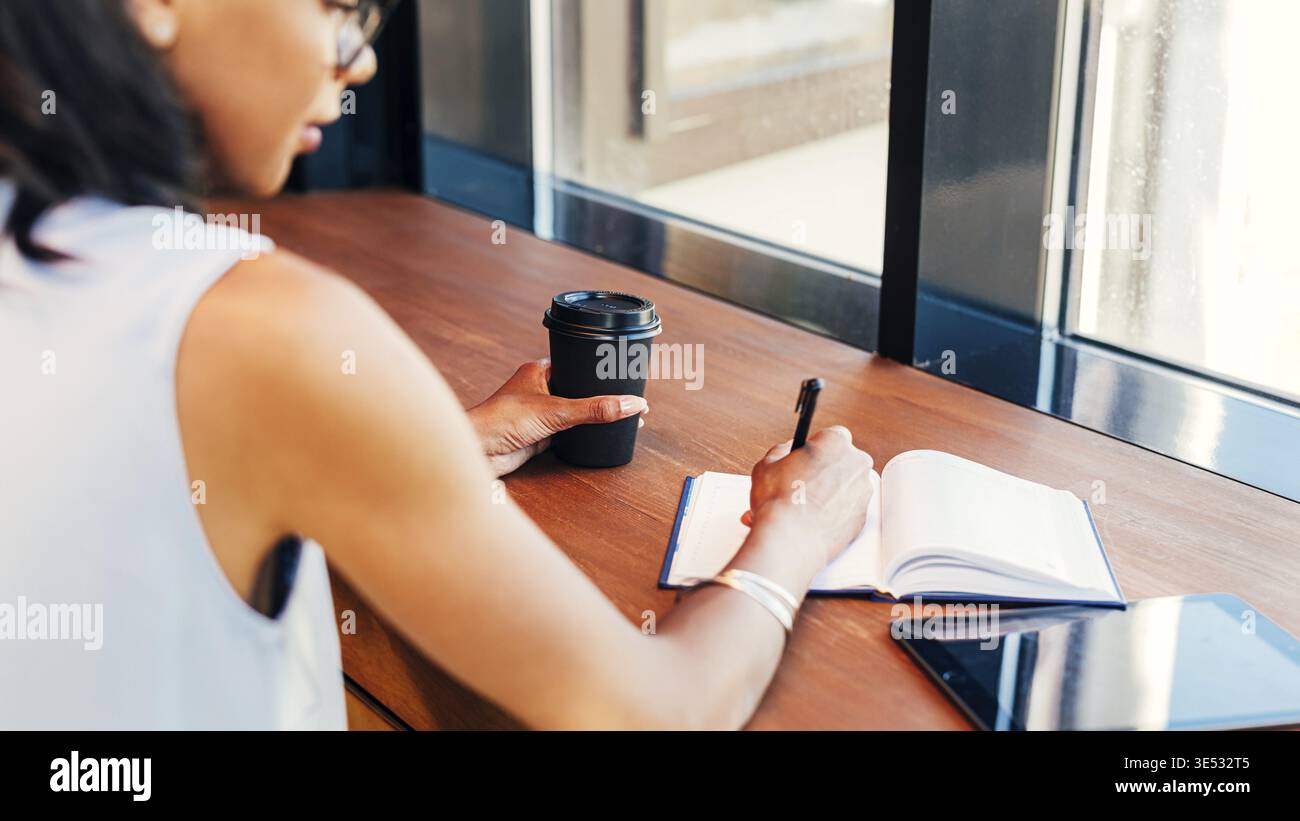 Young entrepreneur taking notes in cafe Stock Photo