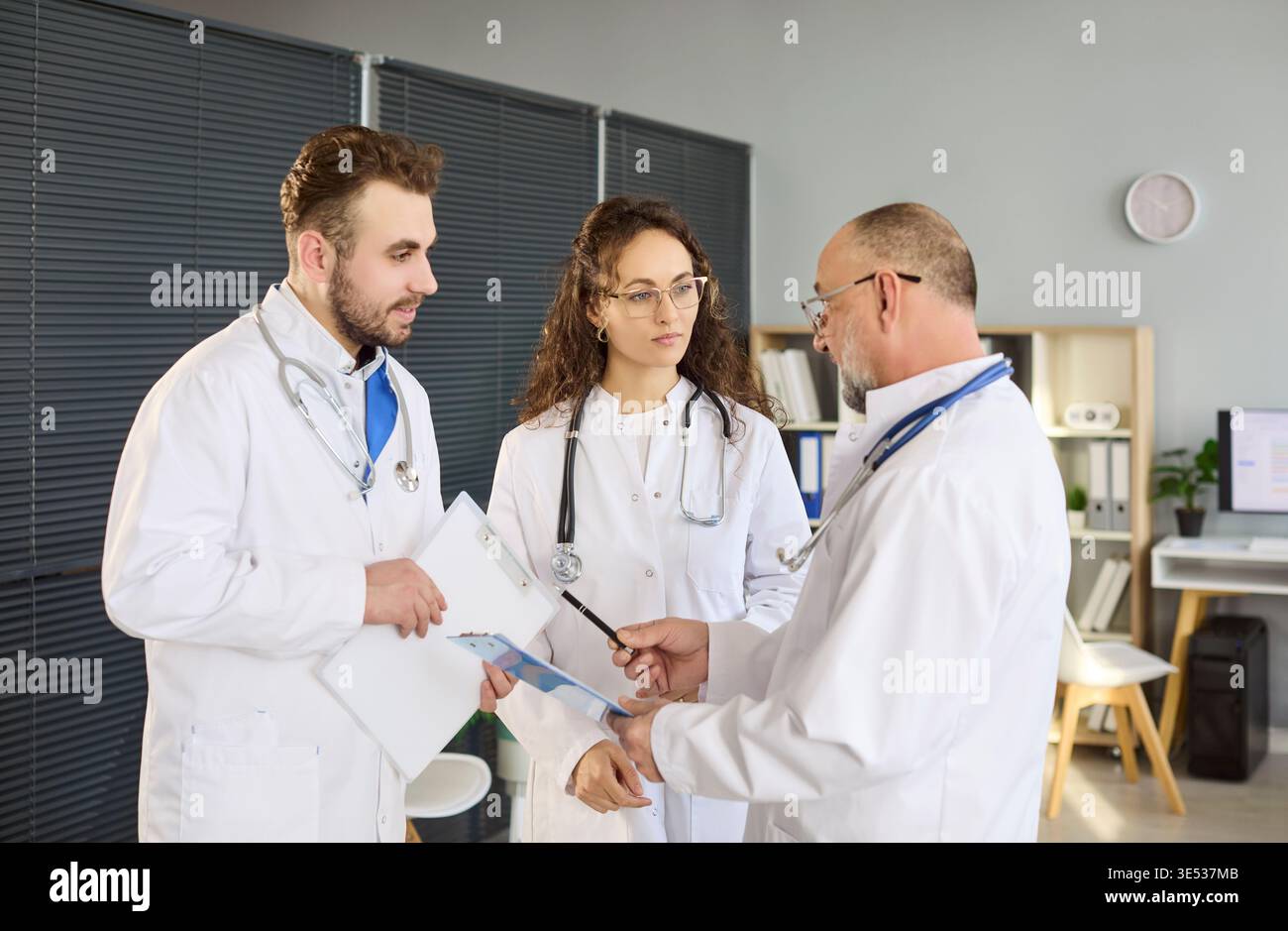 Medical colleagues discussing patient charts in collaborative clinic briefing Stock Photo