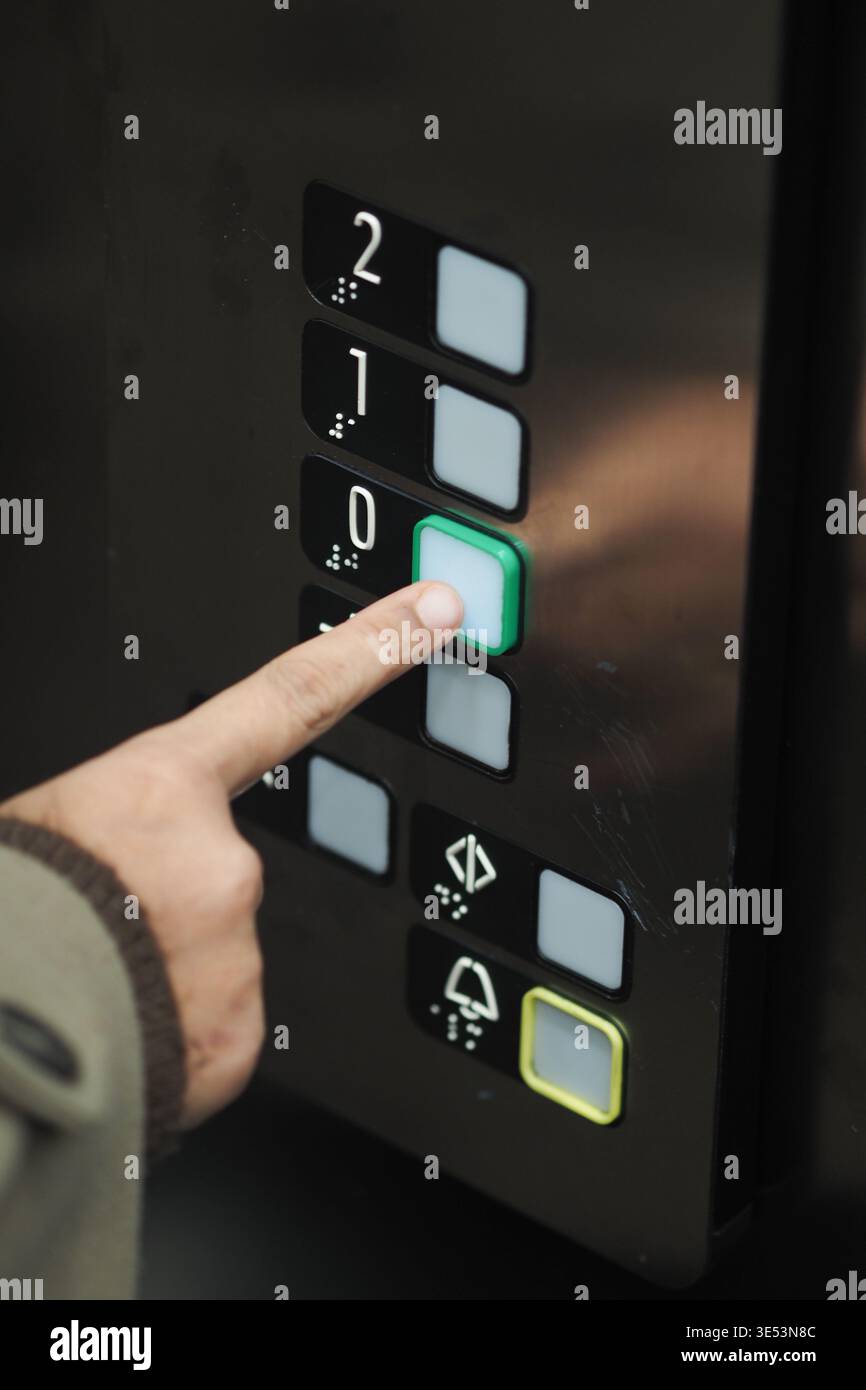 Person presses button in an elevator to go down Stock Photo
