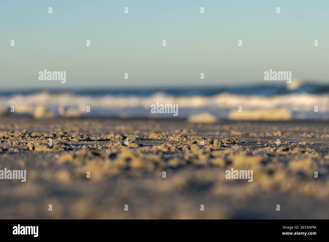 Macro Texture of Sandy Beach with Blurred Ocean Waves at Golden Hour Stock Photo