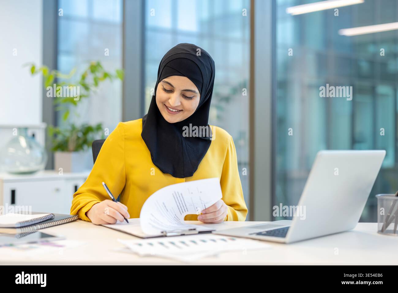 Muslim businesswoman wearing a hijab working at her desk in a modern ...