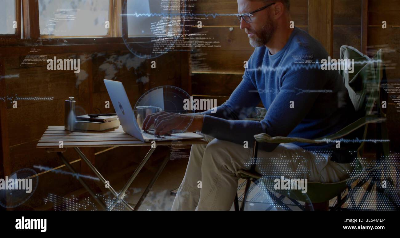 Man typing on laptop in cabin, bringing HUD overlays with code, waveforms, map dots for coding Stock Photo
