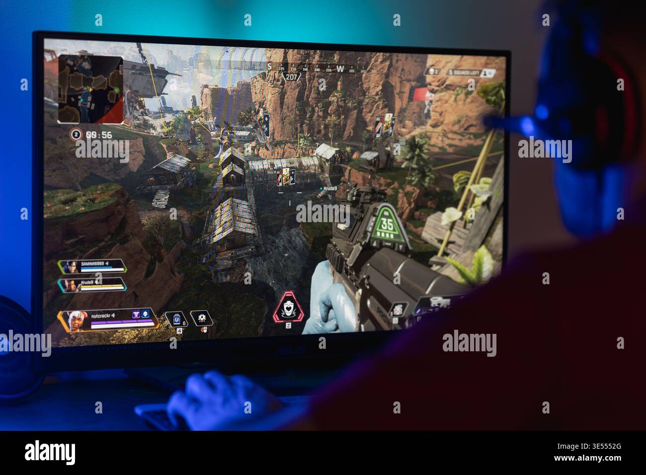 Gamer playing Apex Legends on a computer monitor, first-person perspective of fast-paced battle royale gameplay featuring character abilities and tact Stock Photo