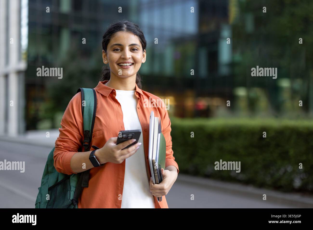 Young indian female student smiling, carrying a backpack and holding ...
