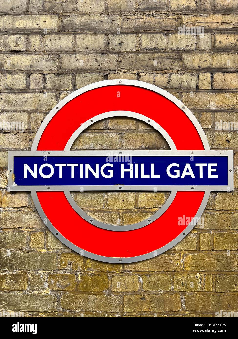A Notting Hill Gate London Underground sign is mounted on a brick pillar - Smartphone Captured Stock Image