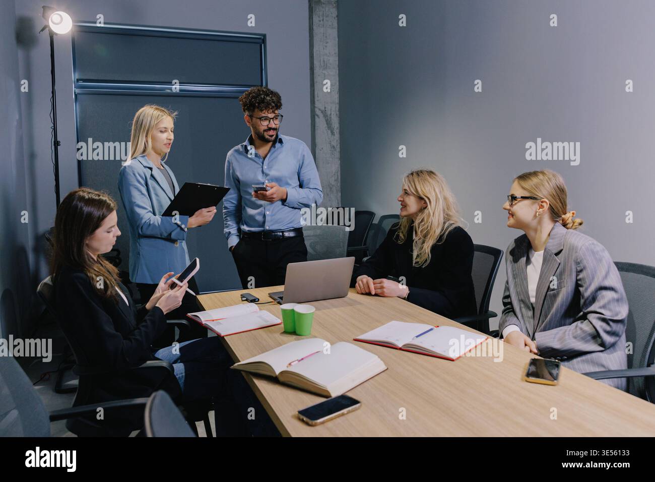 Diverse business colleagues holding a team meeting, discussing ideas and planning projects in a modern shared office space Stock Photo