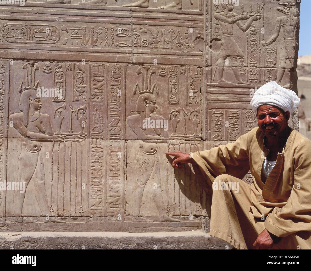 Egypt. Aswan. Temple of Kom Ombo. Local man pointing at frieze. Stock Photo