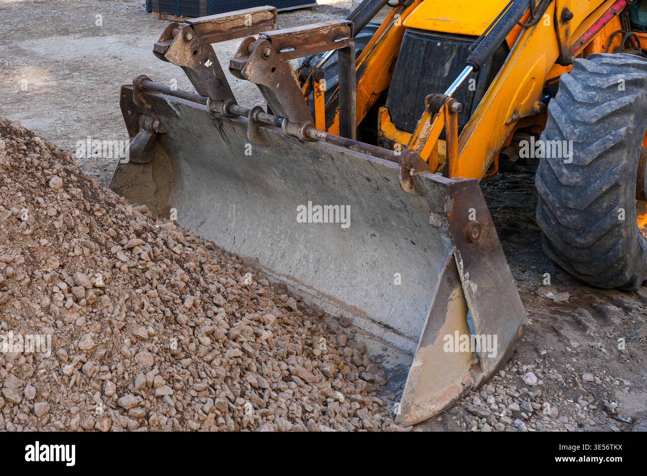 Front loader bucket moving gravel at construction site with heavy machinery and earthworks detail Stock Photo