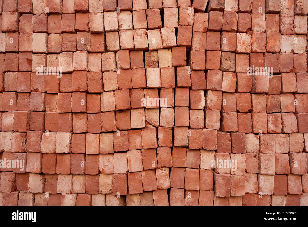 Stack of red bricks arranged end-on, close-up texture background for construction industry Stock Photo
