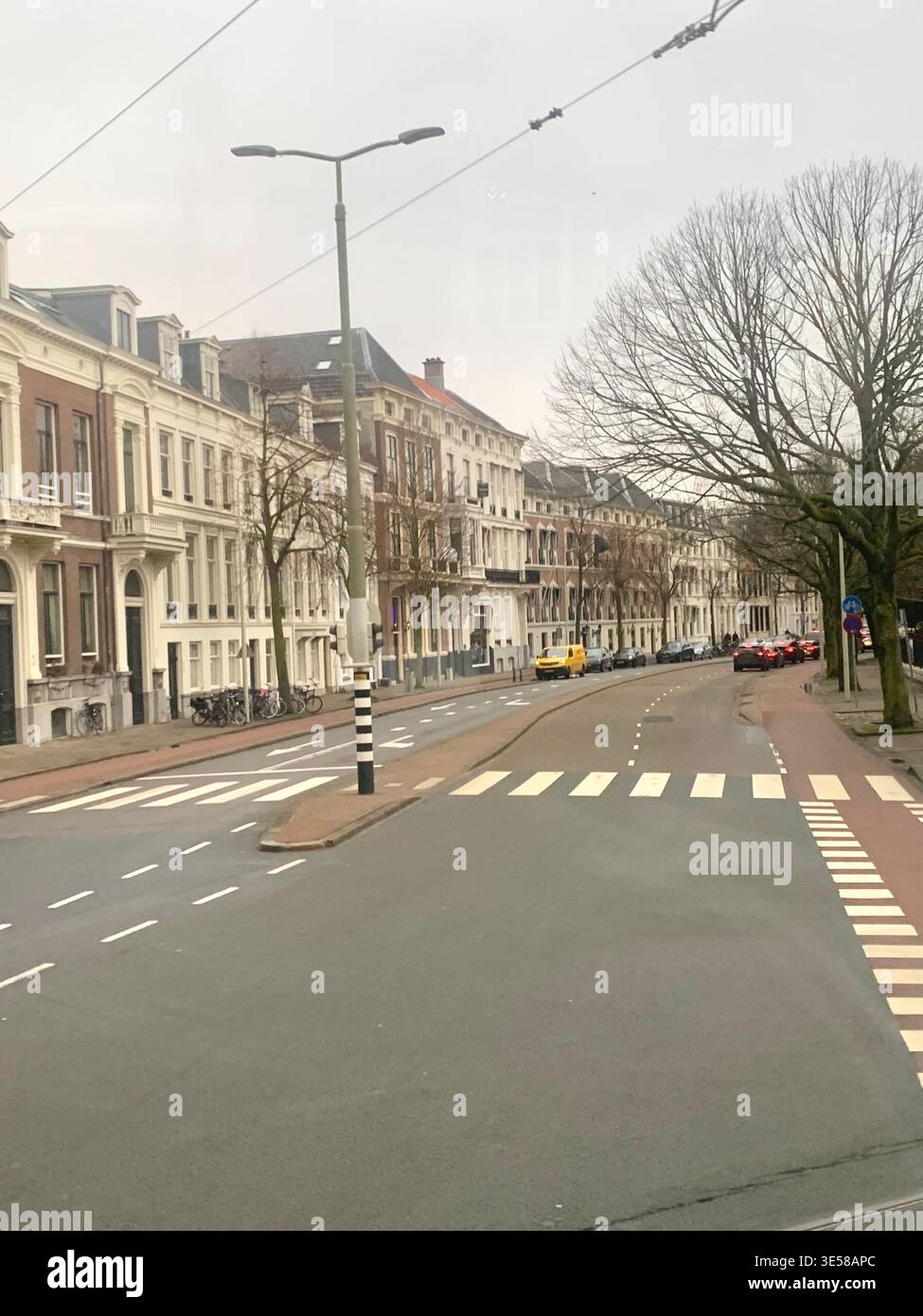 Historic European style townhouse with decorative facade and coloured flags displayed on the upper floors overlooking a tram lined street in Hague - Smartphone Captured Stock Image