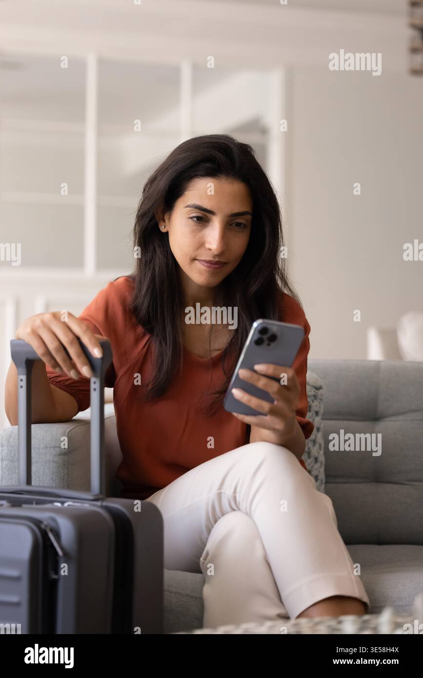 Woman using smartphone while waiting to travel Stock Photo