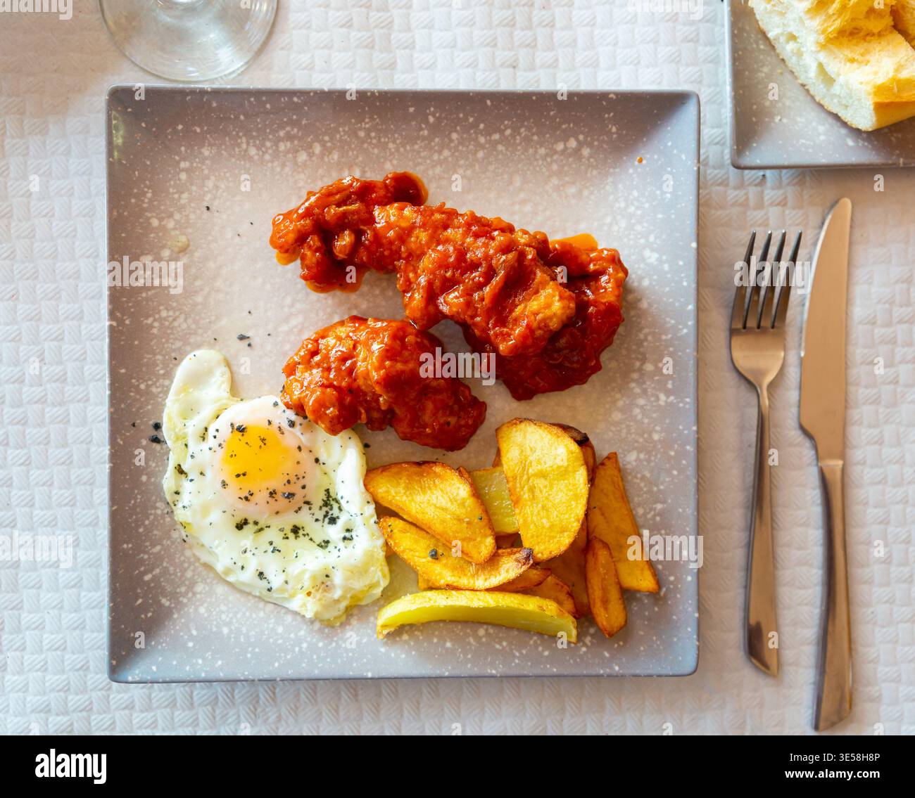 Baked potatoes with chicken in sauce and fried egg at plate Stock Photo