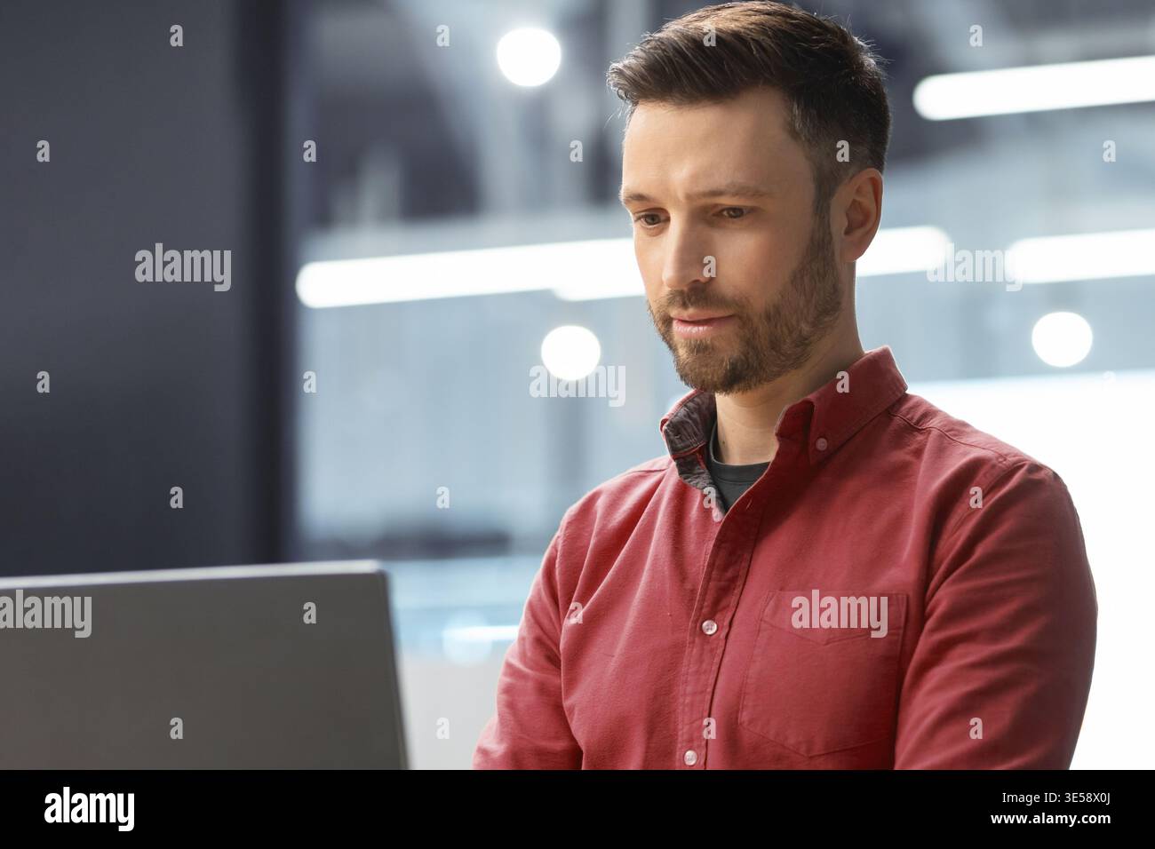 Man Using Laptop in Modern Office Setting During Work Hours Stock Photo