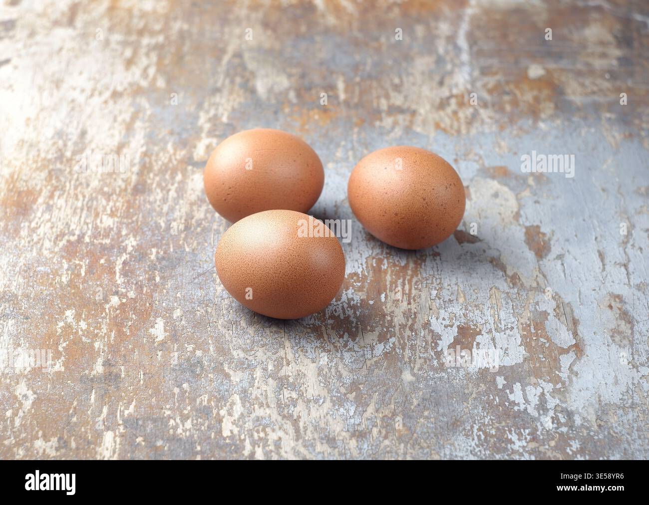 Three brown eggs on an old wooden background. Stock Photo