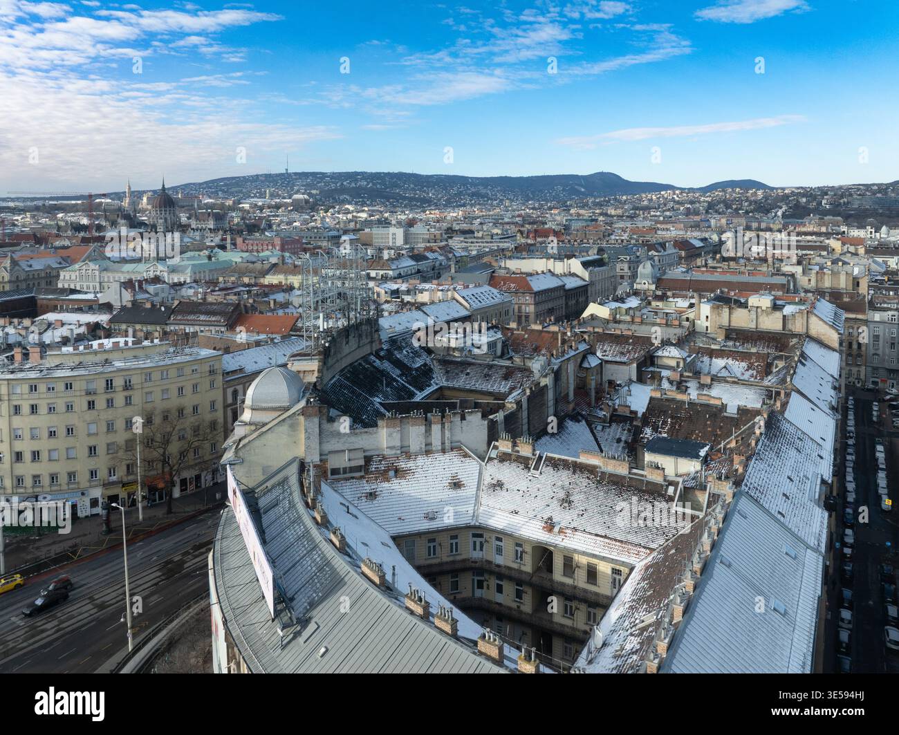 Wide panoramic view from St Stephen's Basilica dome, snow rooftops, Parliament left, Danube bridges, Buda Hills, blue sky Stock Photo