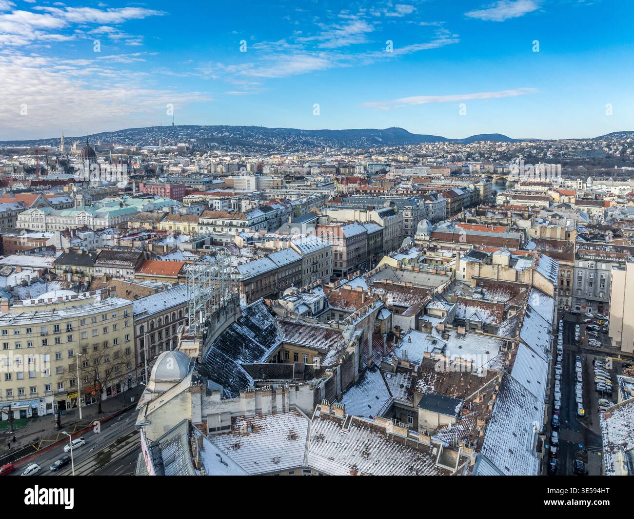 Wide panoramic view from St Stephen's Basilica dome, snow rooftops, Parliament left, Danube bridges, Buda Hills, blue sky Stock Photo