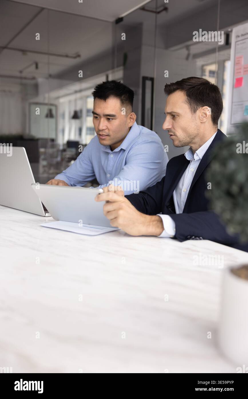 Two multicultural businessmen colleagues developing project using digital tablet notebook Stock Photo