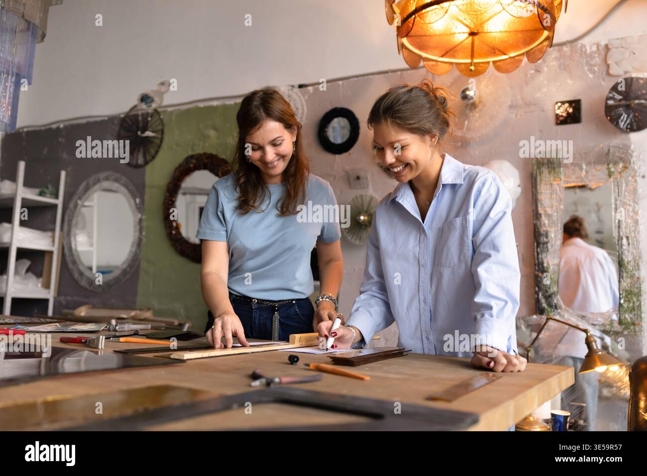 Craftswomen colleagues collaborating on glass work design Stock Photo